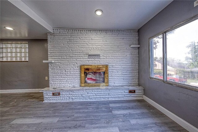 unfurnished living room with brick wall and hardwood / wood-style flooring