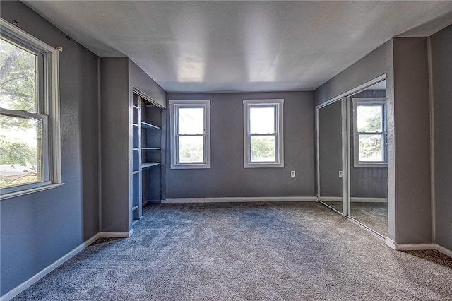 unfurnished bedroom with multiple windows, a closet, and carpet floors