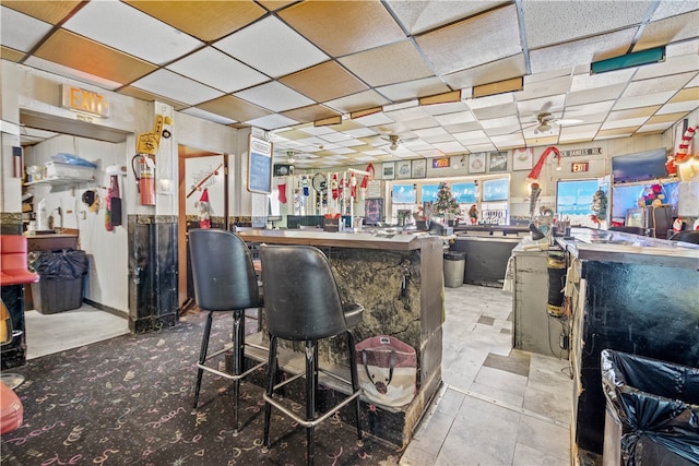 bar featuring ceiling fan, light tile patterned flooring, and a paneled ceiling