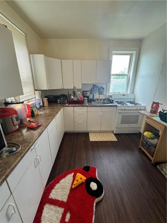 175 Penn Ave, Mount Oliver, PA 15210 - kitchen with white gas stove, dark wood finished floors, a sink, dark countertops, and white cabinets