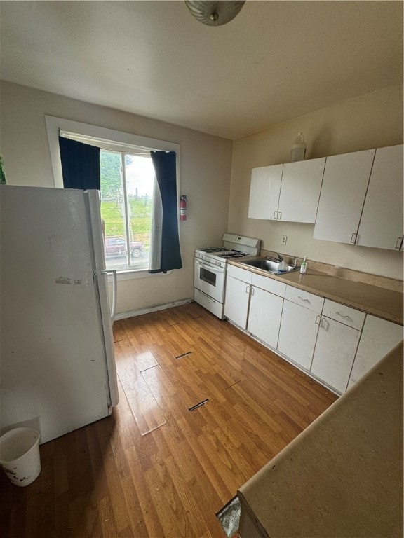 kitchen featuring white cabinets, light wood-type flooring, sink, and white appliances