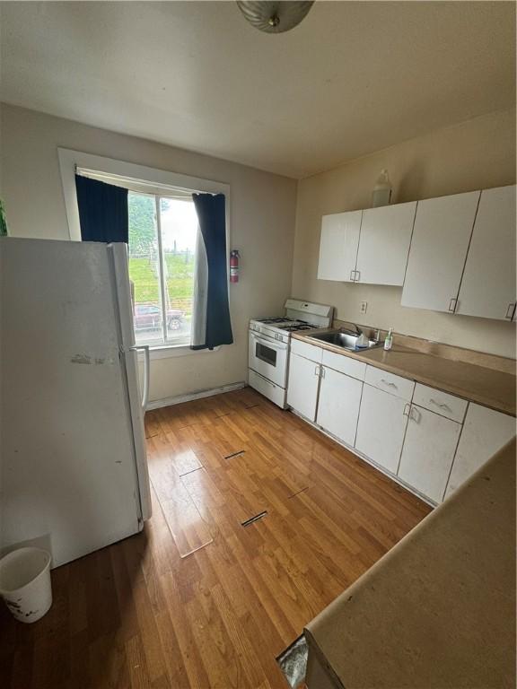 175 Penn Ave, Mount Oliver, PA 15210 - kitchen with white cabinets, a sink, light wood-type flooring, and white appliances