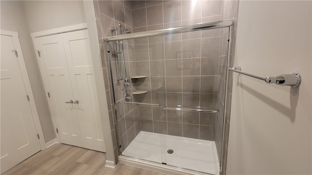 bathroom with wood-type flooring and an enclosed shower