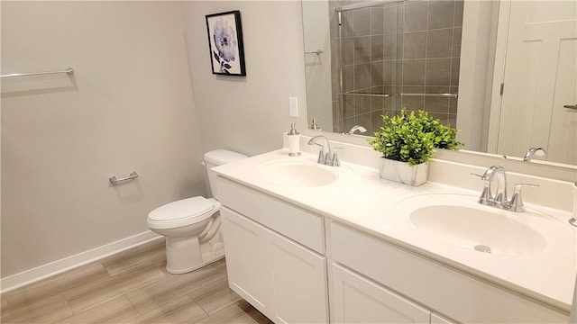 bathroom with toilet, a tile shower, and vanity