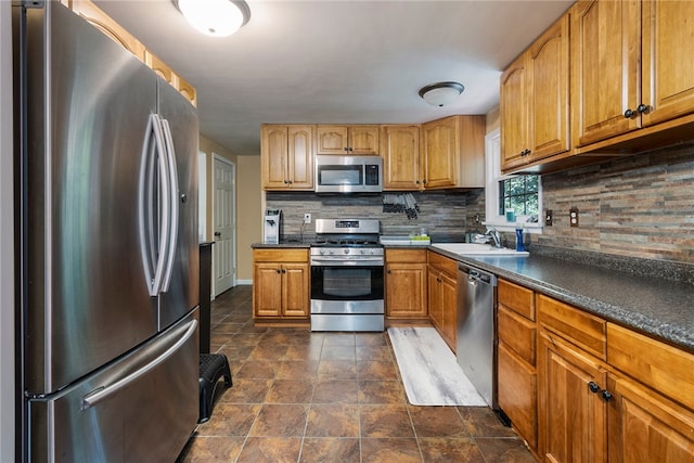 kitchen featuring dark tile patterned flooring, stainless steel appliances, sink, and decorative backsplash