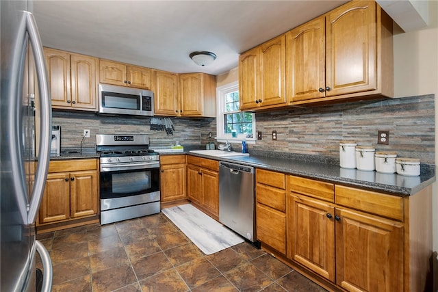 kitchen featuring sink, stainless steel appliances, dark tile patterned floors, and decorative backsplash