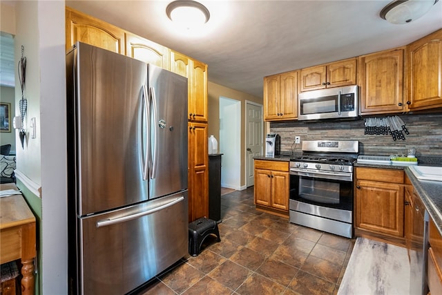 kitchen with decorative backsplash, dark tile patterned floors, and stainless steel appliances