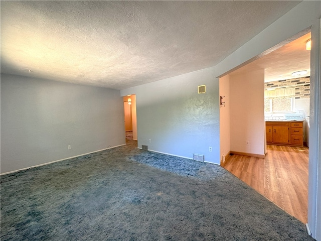 carpeted empty room with a textured ceiling