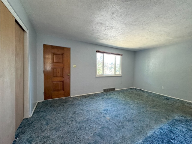 carpeted empty room featuring a textured ceiling