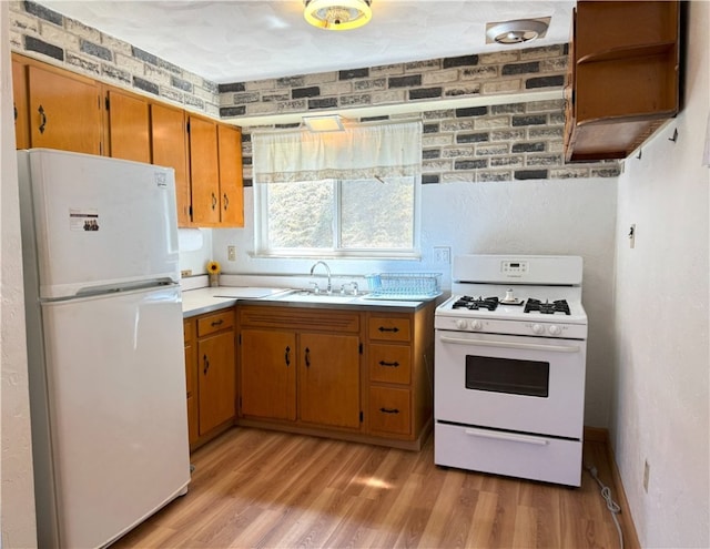 kitchen featuring sink, light wood-type flooring, and white appliances