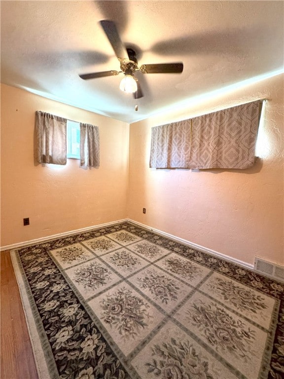 unfurnished room featuring a ceiling fan, visible vents, a textured ceiling, and baseboards