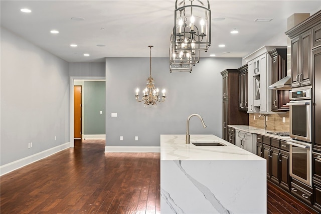 kitchen with a center island with sink, sink, decorative light fixtures, dark hardwood / wood-style flooring, and dark brown cabinets