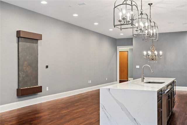 kitchen featuring light stone countertops, sink, hanging light fixtures, and dark wood-type flooring