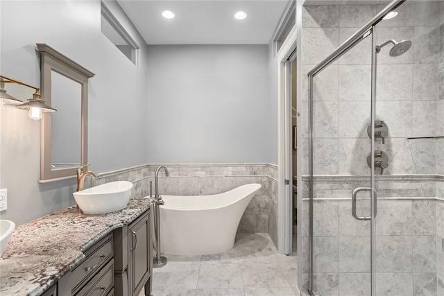 bathroom with vanity, tile walls, and shower with separate bathtub