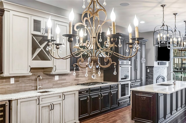 kitchen with light stone countertops, appliances with stainless steel finishes, dark hardwood / wood-style flooring, and a kitchen island with sink