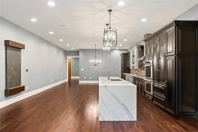 kitchen featuring sink, hanging light fixtures, dark hardwood / wood-style floors, a spacious island, and decorative backsplash