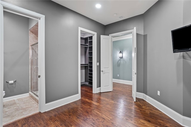 unfurnished bedroom with dark hardwood / wood-style flooring, a walk in closet, ensuite bathroom, and a closet