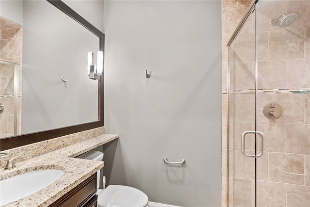 bathroom with vanity, toilet, and a shower with door