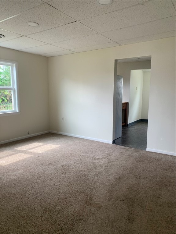 carpeted empty room featuring a paneled ceiling