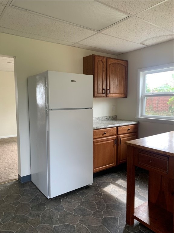 kitchen with a paneled ceiling, dark tile patterned floors, and white fridge