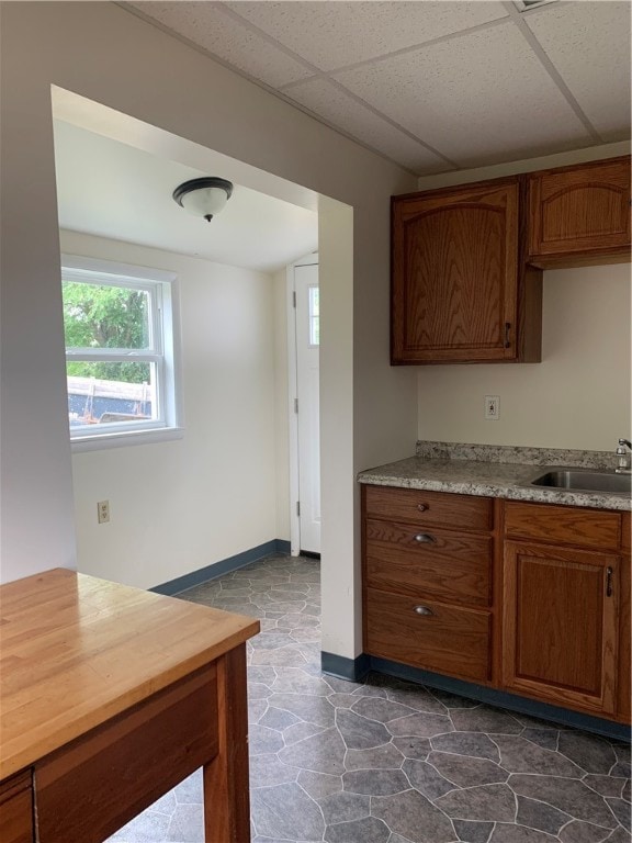 kitchen featuring a drop ceiling, dark tile patterned flooring, sink, and light stone countertops