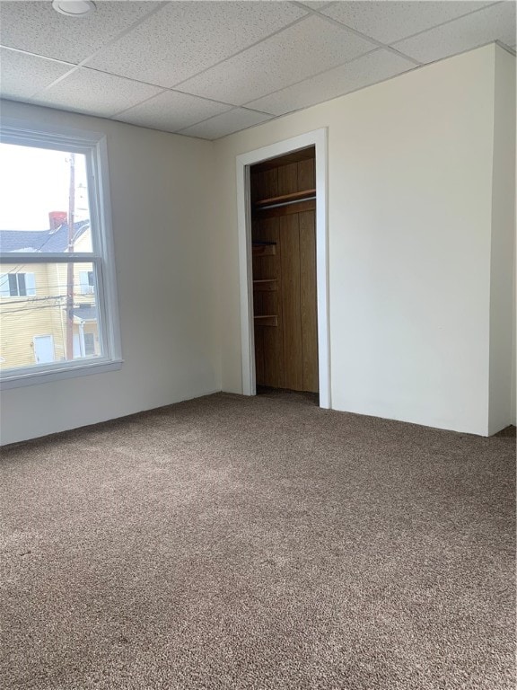 unfurnished room with carpet floors and a drop ceiling