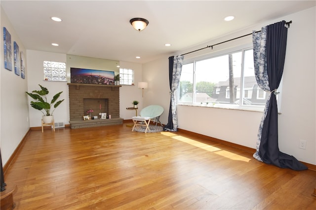 living room featuring plenty of natural light, light hardwood / wood-style flooring, and a brick fireplace