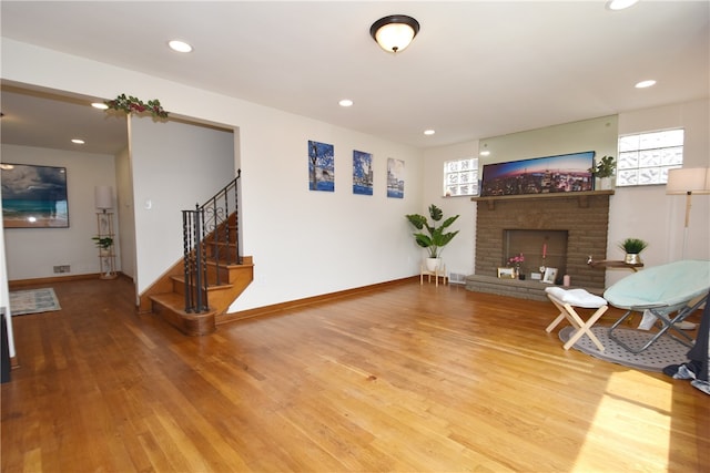 living room with hardwood / wood-style floors and a brick fireplace