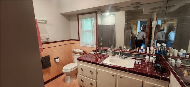 bathroom with vanity, tile patterned flooring, tile walls, toilet, and walk in shower