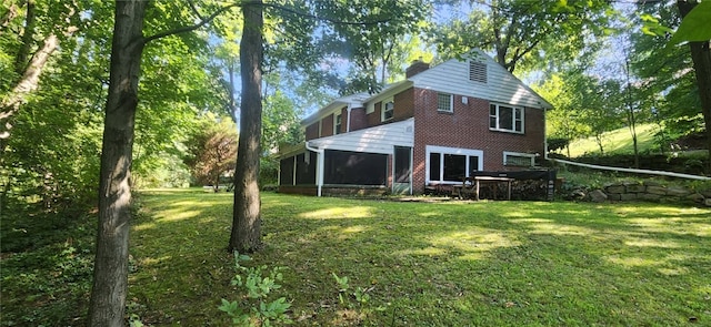 rear view of property with a sunroom and a lawn