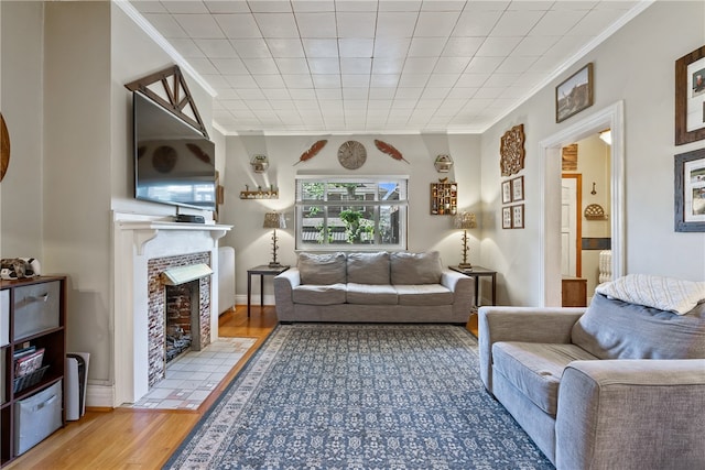 living room with crown molding, light hardwood / wood-style flooring, and a tile fireplace