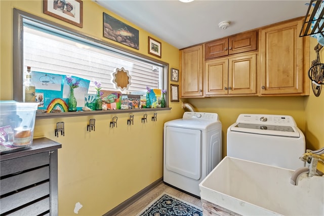 laundry area with light hardwood / wood-style flooring, cabinets, sink, and washing machine and dryer