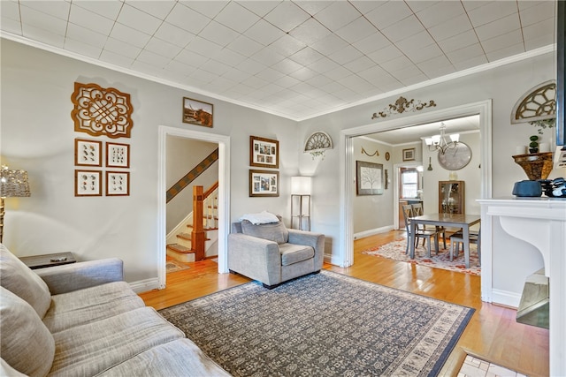 living room featuring ornamental molding, a notable chandelier, and light hardwood / wood-style flooring