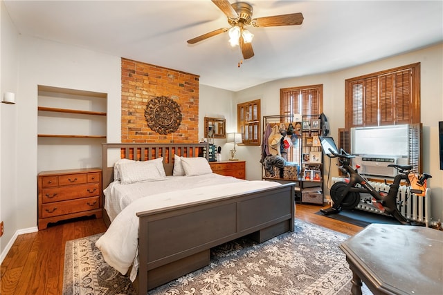 bedroom featuring ceiling fan, hardwood / wood-style flooring, and brick wall