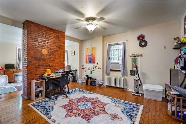 home office with brick wall, cooling unit, radiator, hardwood / wood-style flooring, and ceiling fan