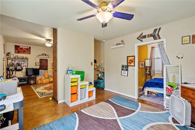 playroom with brick wall, ceiling fan, and wood-type flooring