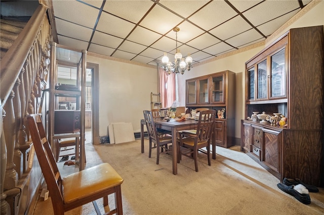 carpeted dining room featuring a chandelier and a drop ceiling