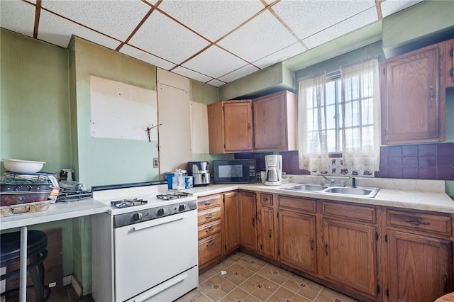 kitchen with sink, white range with gas stovetop, a paneled ceiling, and light tile patterned floors