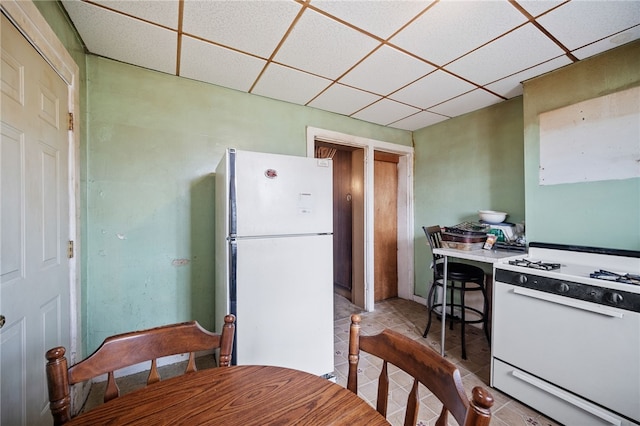 kitchen with light tile patterned flooring, a drop ceiling, and white appliances