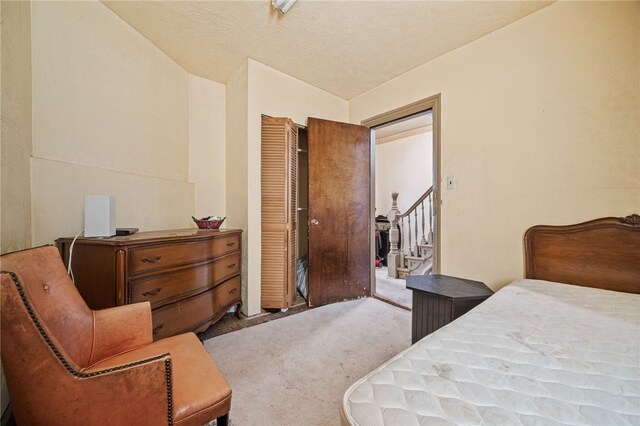 carpeted bedroom featuring a closet, vaulted ceiling, and a textured ceiling