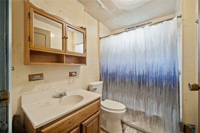 bathroom with a shower with shower curtain, toilet, vanity, and tile walls