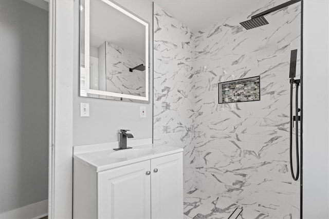 bathroom with tiled shower and vanity