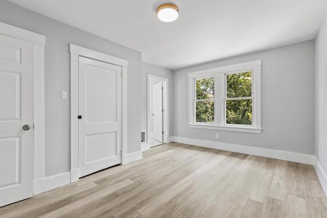 unfurnished bedroom featuring visible vents, baseboards, and wood finished floors