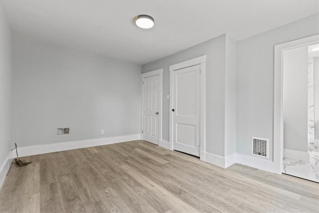 unfurnished bedroom featuring wood finished floors, visible vents, and baseboards