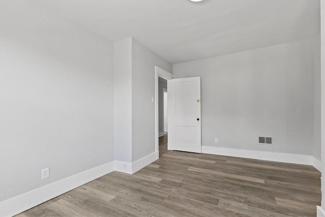 unfurnished room featuring visible vents, baseboards, and wood finished floors