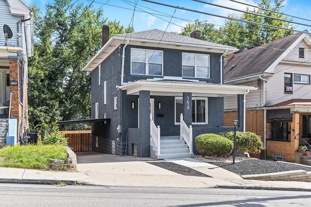 american foursquare style home featuring covered porch, a chimney, concrete driveway, and brick siding