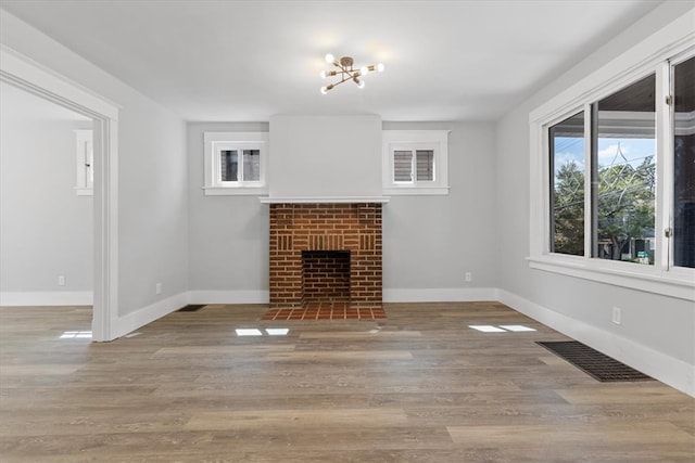 unfurnished living room featuring hardwood / wood-style flooring and a brick fireplace