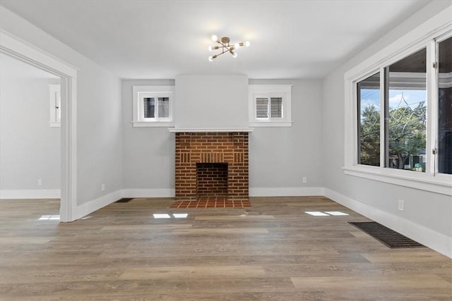 unfurnished living room featuring a fireplace, wood finished floors, visible vents, and baseboards