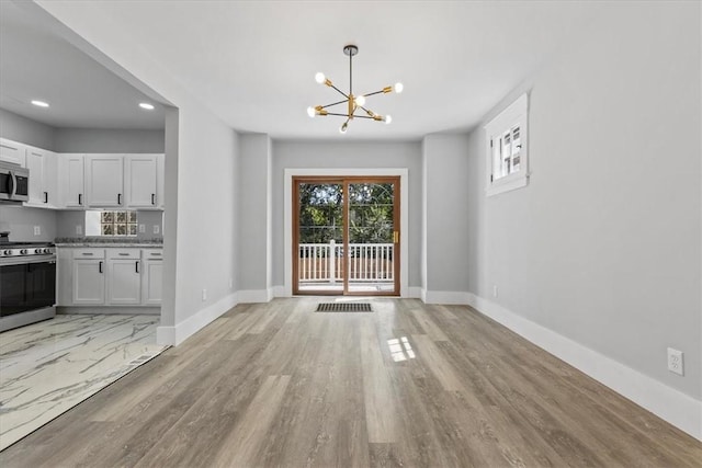 doorway with a chandelier, light wood-style flooring, and baseboards