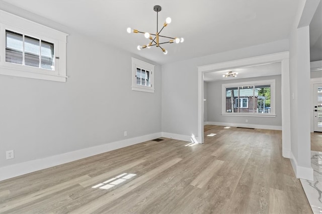 spare room featuring light hardwood / wood-style floors and an inviting chandelier